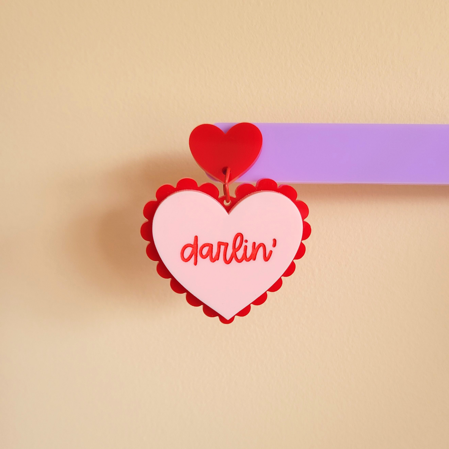 Heart-shaped pink tag with 'darlin' text and red heart on a beige background