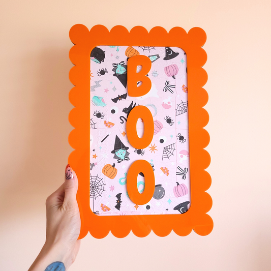 BOO Halloween wall art with orange scalloped acrylic frame and handmade decoupage print featuring witches, pumpkins, bats, and spider webs.