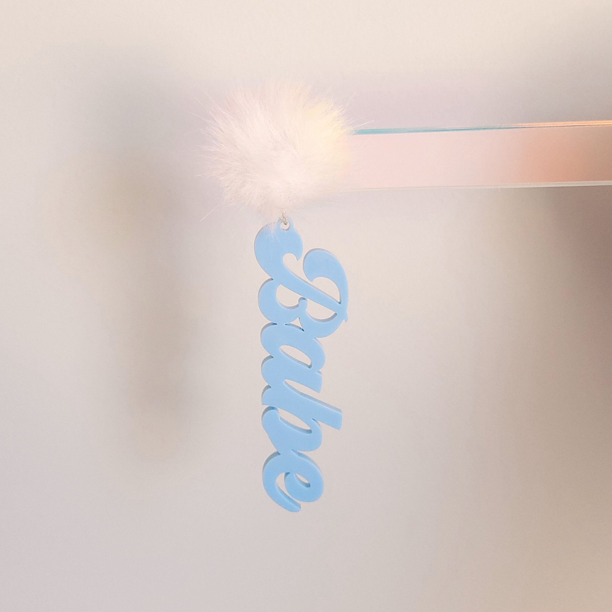 Blue "Babe" Earring with a fluffy white pom pom on a white background 