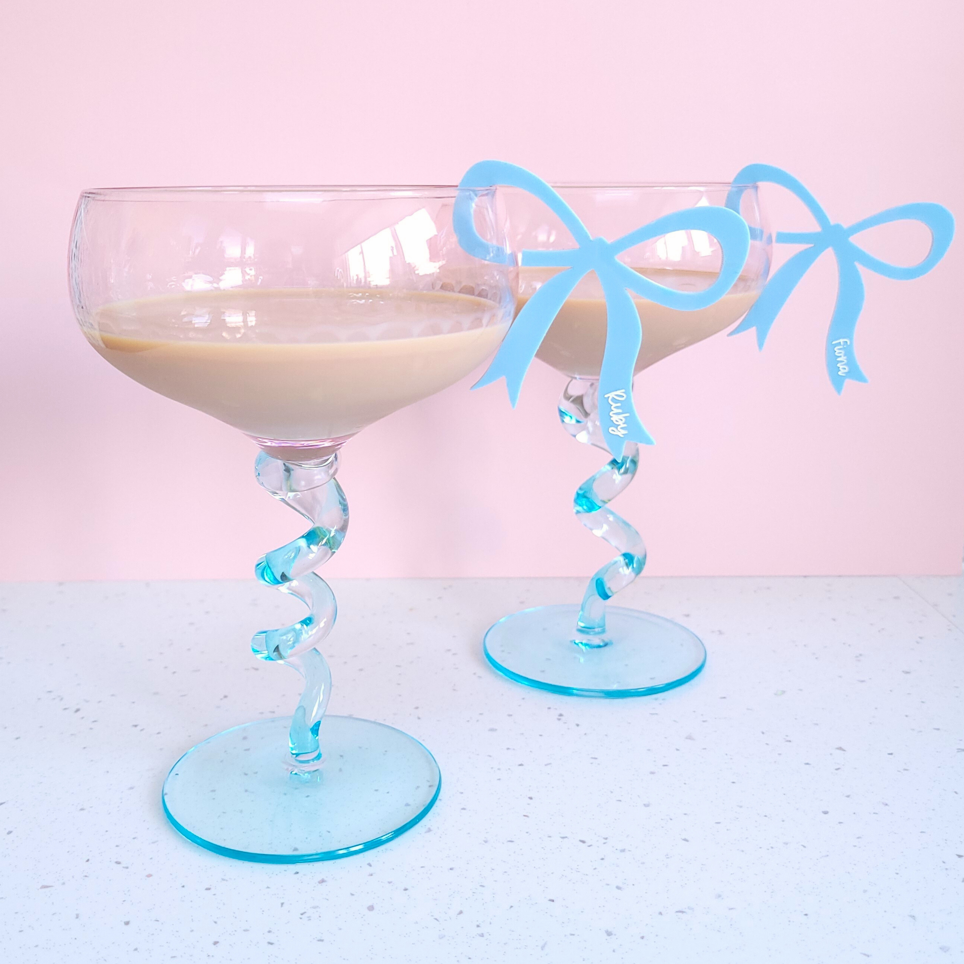Blue acrylic bow drink charms with personalised names Fiona and Ruby clipped on glasses