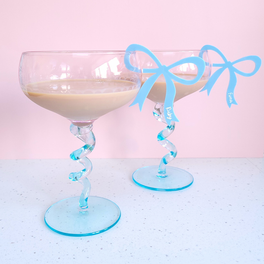 Blue acrylic bow drink charms with personalised names Fiona and Ruby clipped on glasses