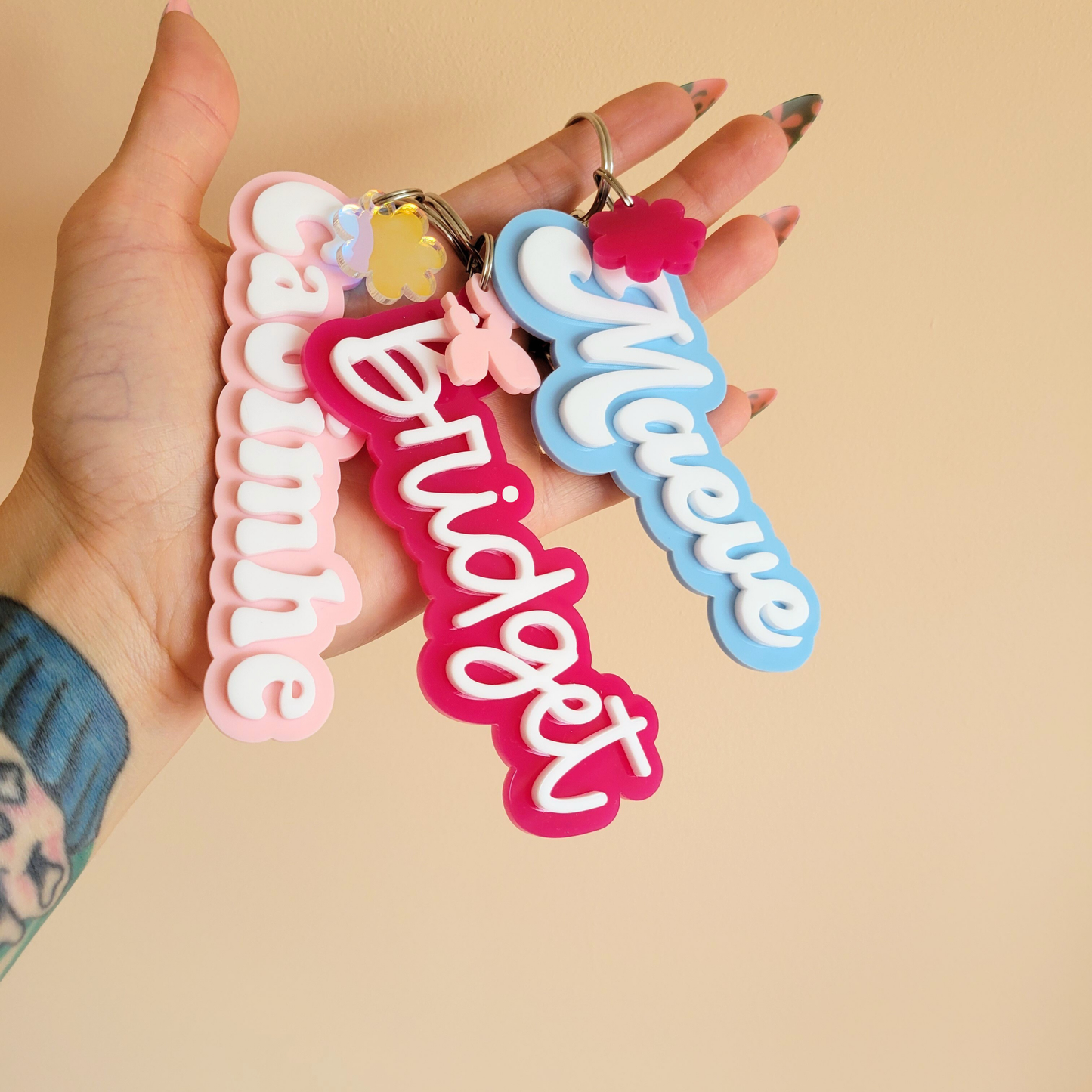 Image of custom acrylic keyrings in bold colours, each personalised with a name and finished with a small charm, handmade by Pop Heart Studio.