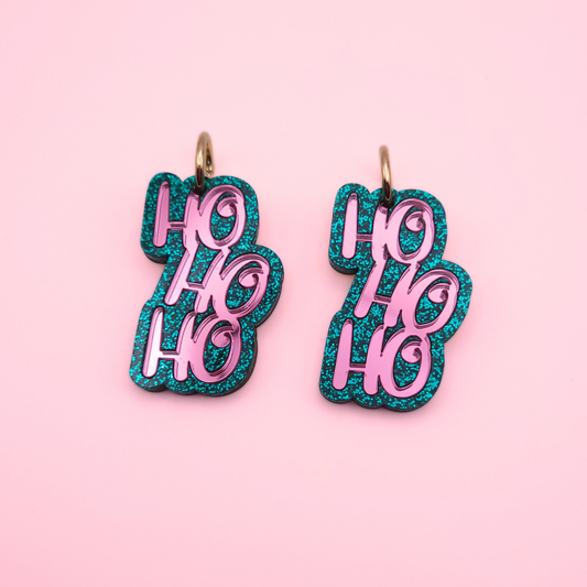 Teal glitter acrylic earrings with pink inlay ‘Ho Ho Ho’ text on gold hoops — festive Christmas jewellery by Pop Heart Studio.
