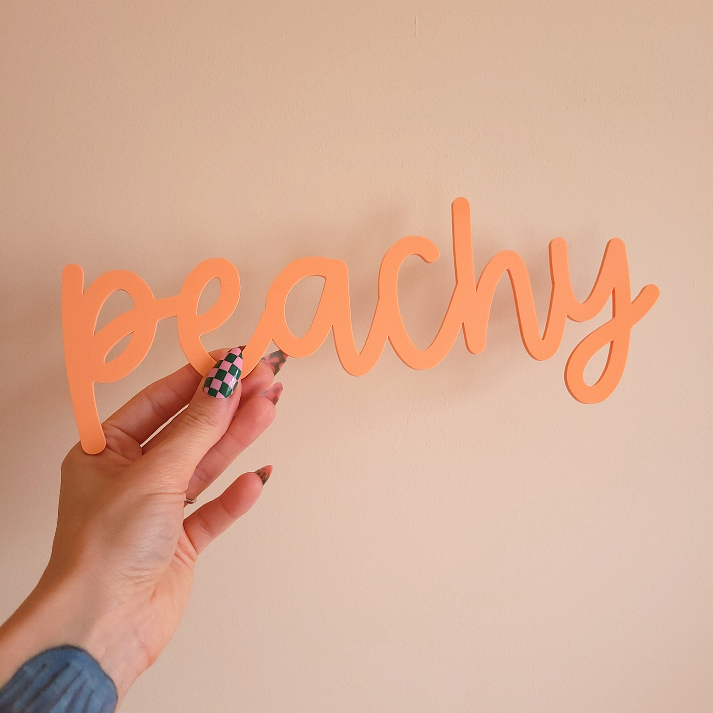 Hand holding playful dopamine decor word sign in peach acrylic, handmade wall art