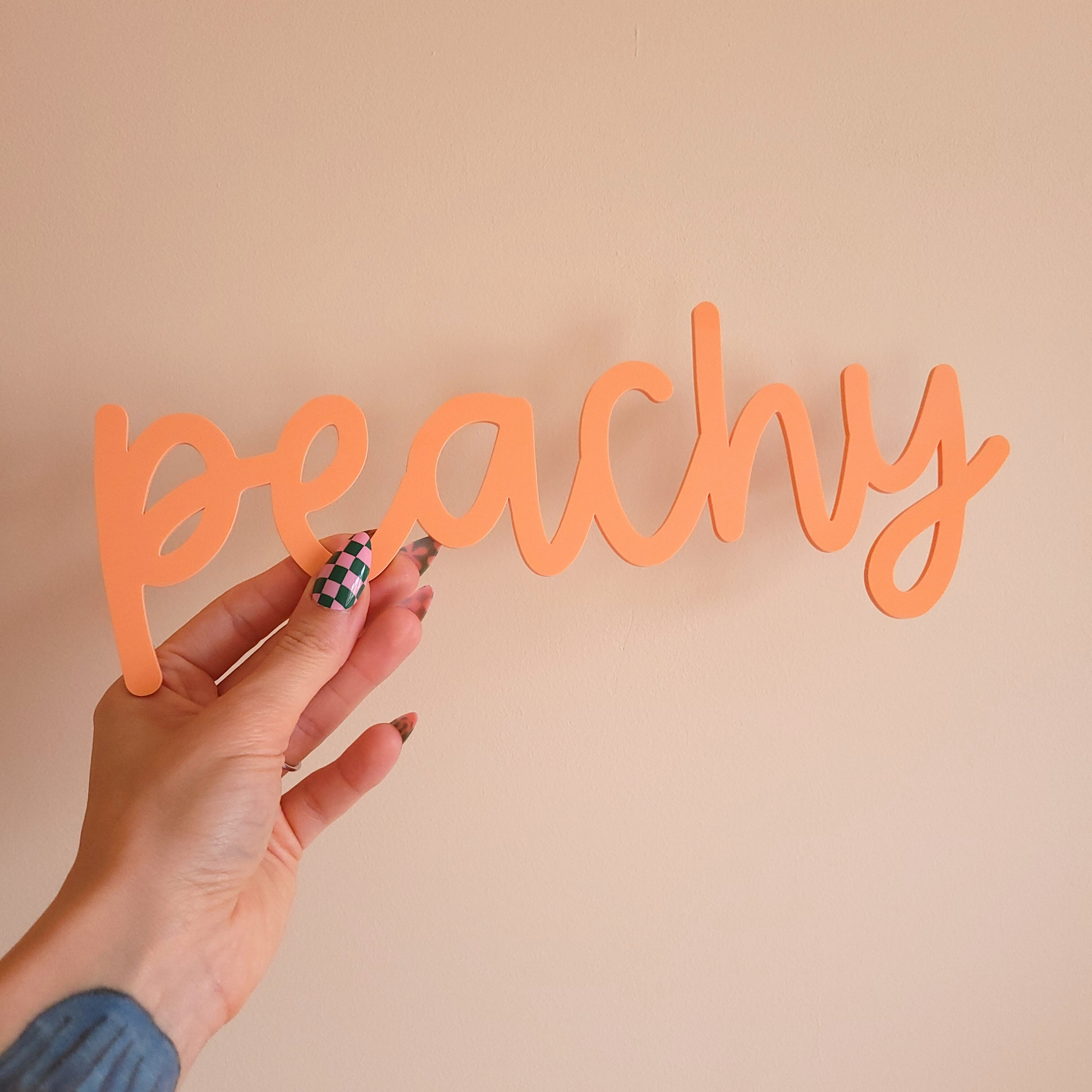 Hand holding playful dopamine decor word sign in peach acrylic, handmade wall art