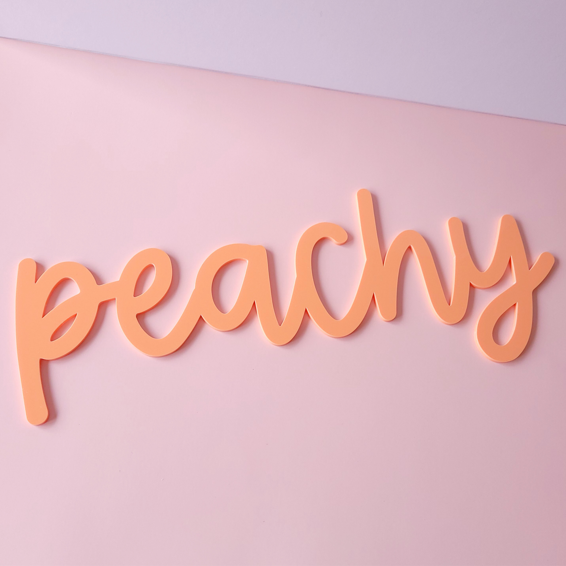 Peachy script acrylic wall sign in pastel peach colour on pink background