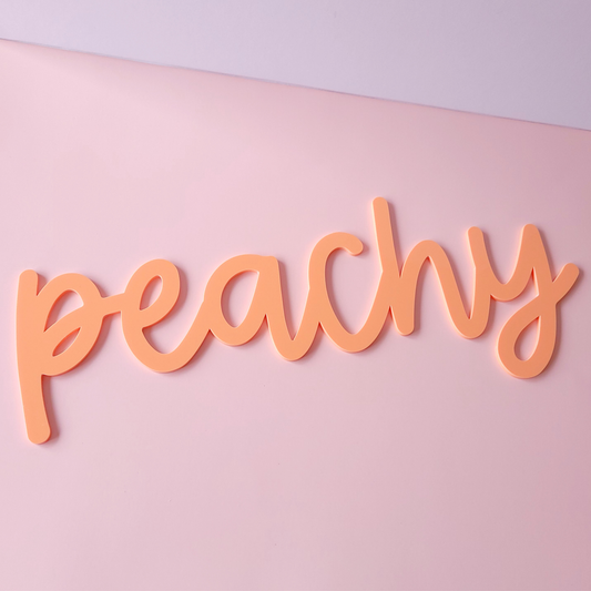 Peachy script acrylic wall sign in pastel peach colour on pink background