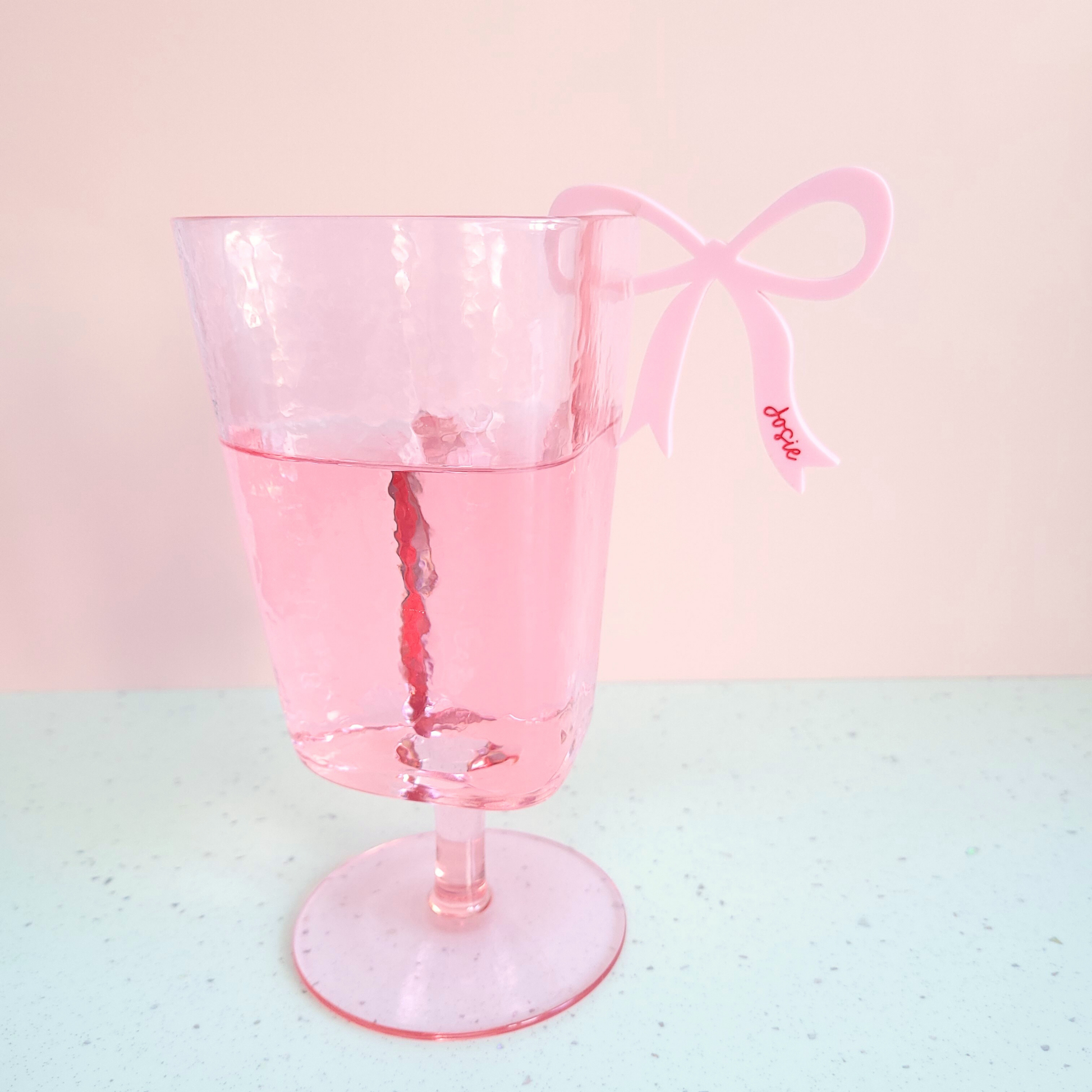 Pink acrylic bow drink charms with personalised name Josie clipped on pink glass