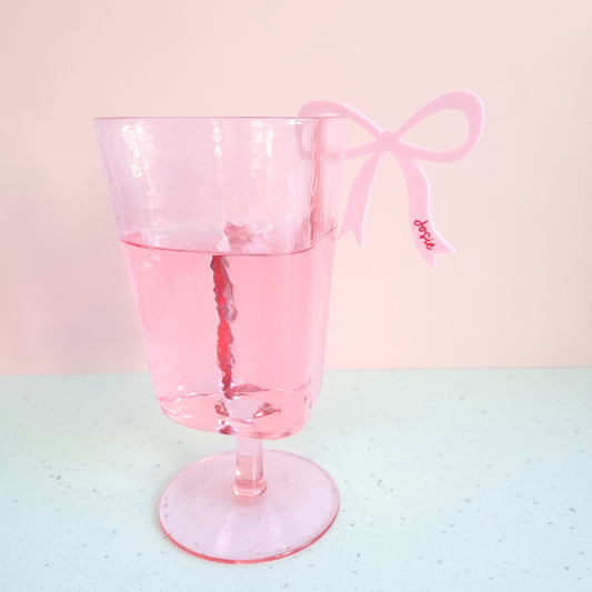 Pink acrylic bow drink charms with personalised name Josie clipped on pink glass