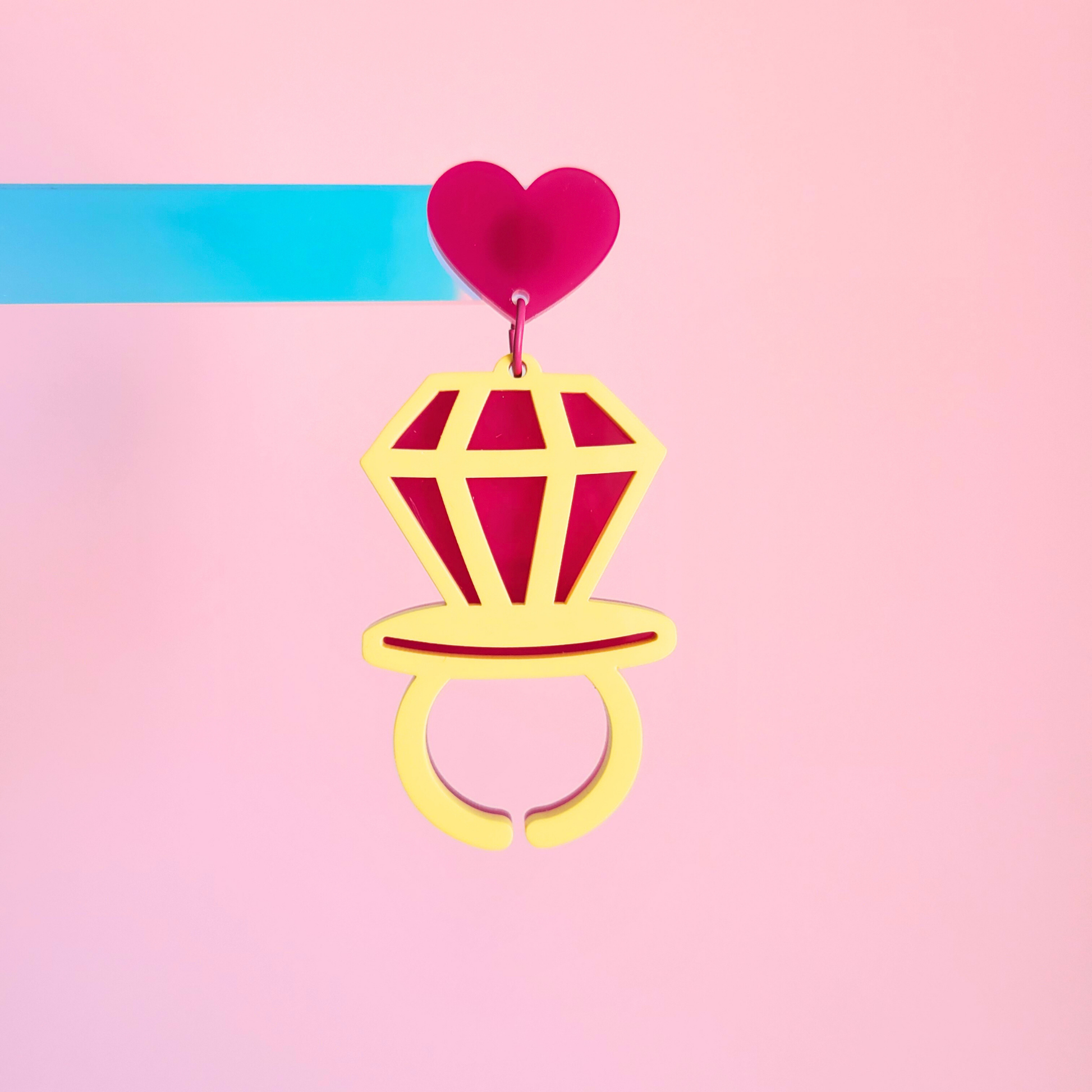 Heart Pop Earrings with a heart-shaped top on a pink background