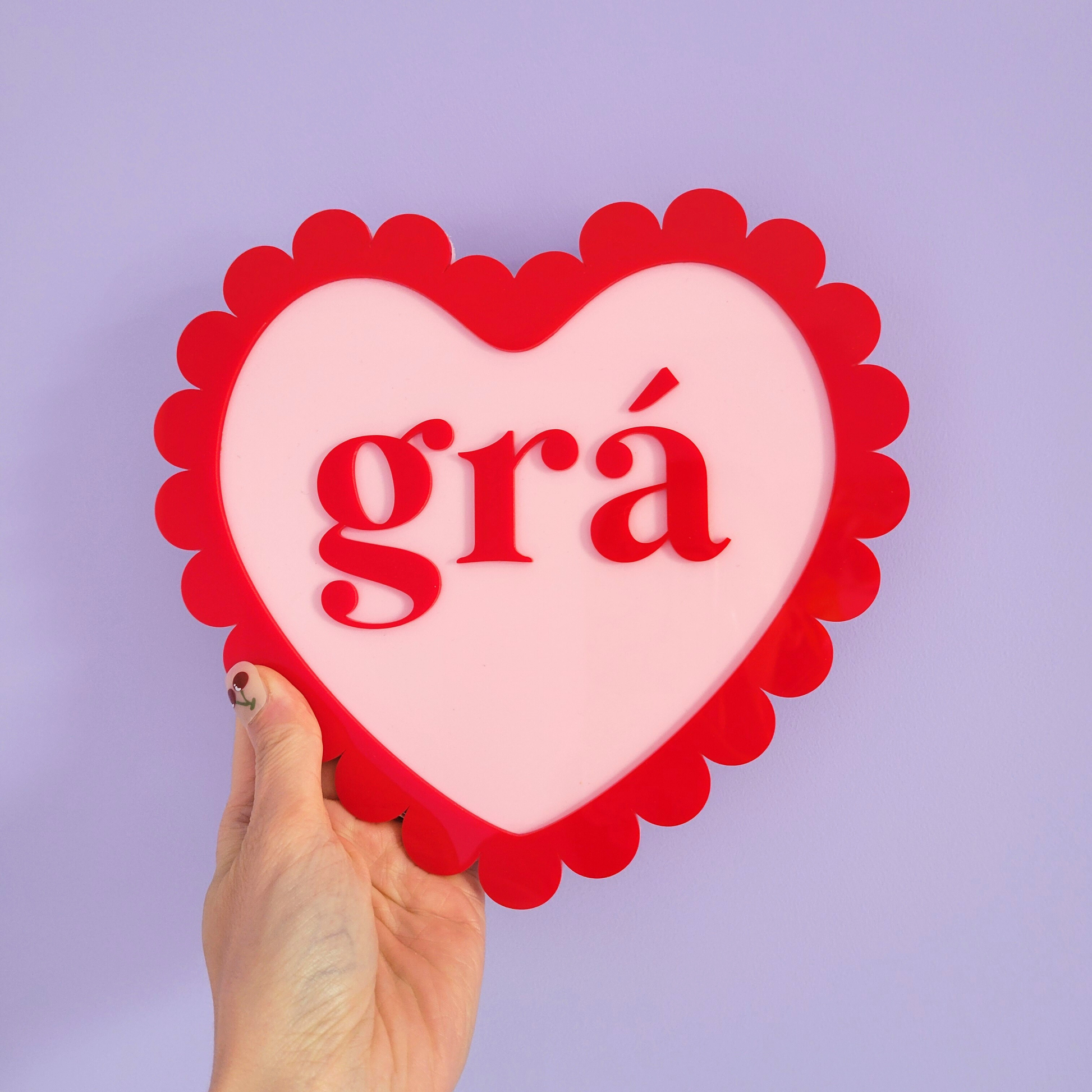 Heart-shaped sign with 'grá' text held against a purple background