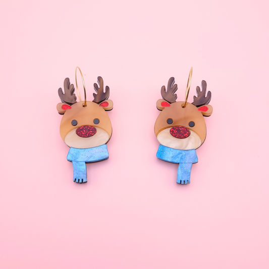 Acrylic reindeer earrings with glitter red nose, brown antlers, and blue winter scarf on gold hoops — festive Christmas jewellery by Pop Heart Studio.