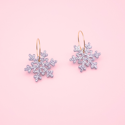 Silver glitter acrylic snowflake earrings on gold hoops — handmade festive winter dangle earrings.